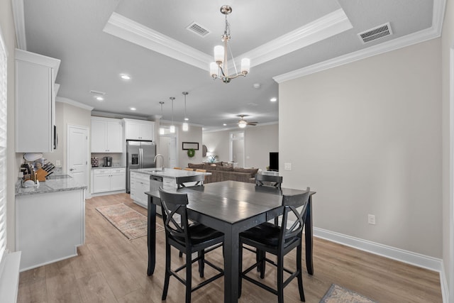 5414 Harmony Ln, Gulf Breeze, FL 32563 - dining space featuring a tray ceiling, ornamental molding, light wood-type flooring, a ceiling fan, and a chandelier