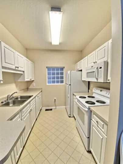 1501 N Partin Dr Unit 216, Niceville, FL 32578 - kitchen featuring white appliances, a sink, light tile patterned floors, light countertops, and white cabinets