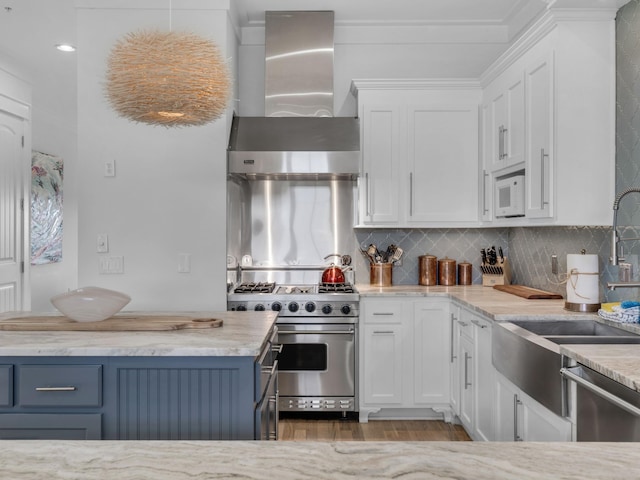 kitchen featuring appliances with stainless steel finishes, wall chimney range hood, white cabinets, and backsplash
