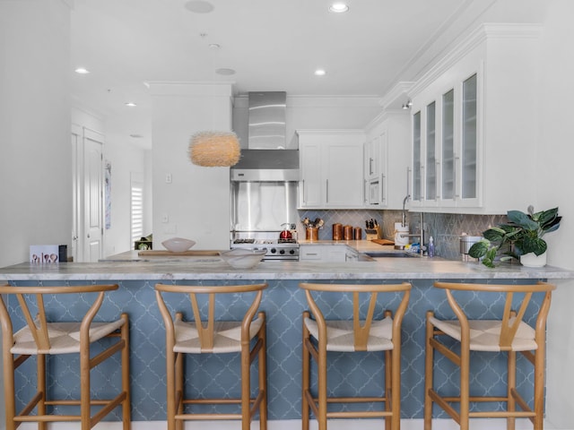kitchen with wall chimney range hood, a sink, white appliances, glass insert cabinets, and backsplash