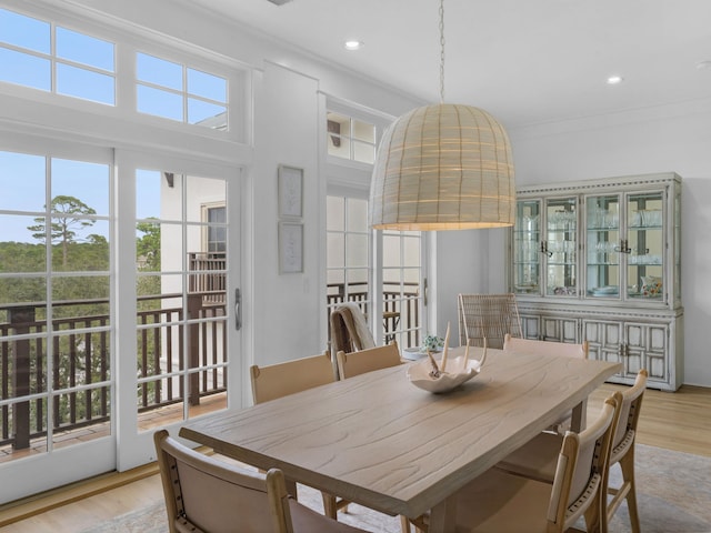 dining space with wood finished floors, crown molding, and recessed lighting