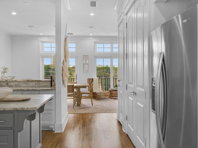 kitchen with stainless steel fridge, wood finished floors, light stone countertops, gray cabinets, and recessed lighting