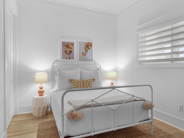 bedroom with wood finished floors, baseboards, and ornamental molding