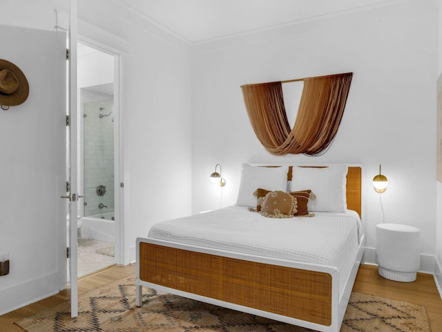 bedroom with light wood finished floors, ensuite bathroom, and ornamental molding