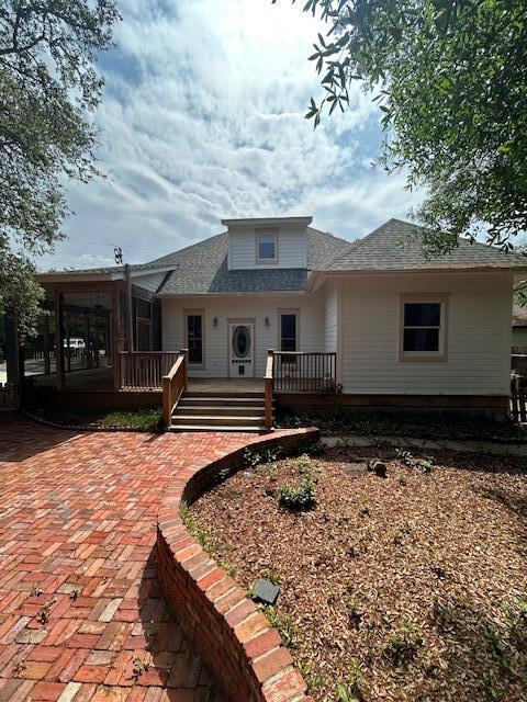 615 Beach Dr, Destin, FL 32541 - view of front of home with a shingled roof, a wooden deck, and a sunroom