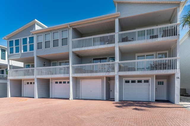 view of apartment building / complex with a garage, cooling unit, and driveway