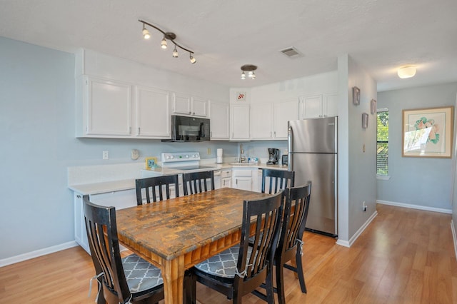 kitchen featuring freestanding refrigerator, black microwave, white electric range oven, and light wood-style flooring
