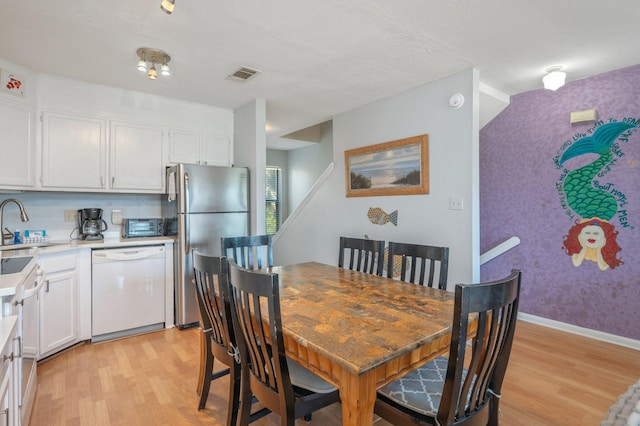 dining space featuring light wood-type flooring and wallpapered walls