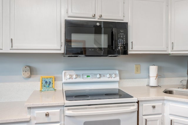 kitchen with black microwave, white range with electric cooktop, light countertops, and white cabinetry