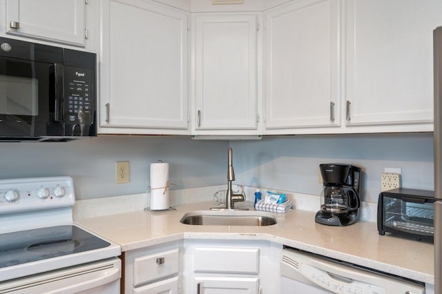kitchen with white appliances, white cabinets, and a sink