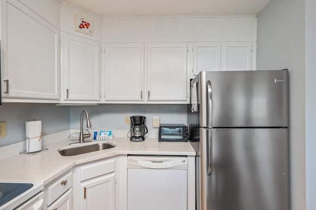 kitchen with freestanding refrigerator, dishwasher, a sink, white cabinets, and light countertops