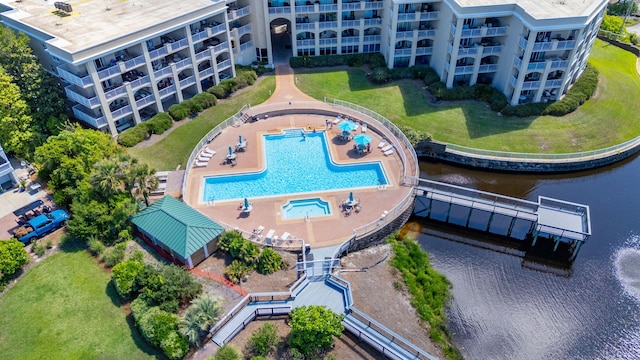 aerial view of a nearby body of water, apartment complex, and a pool area