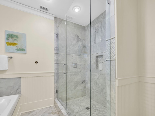 full bathroom featuring wainscoting, a shower stall, a garden tub, and marble finish floors