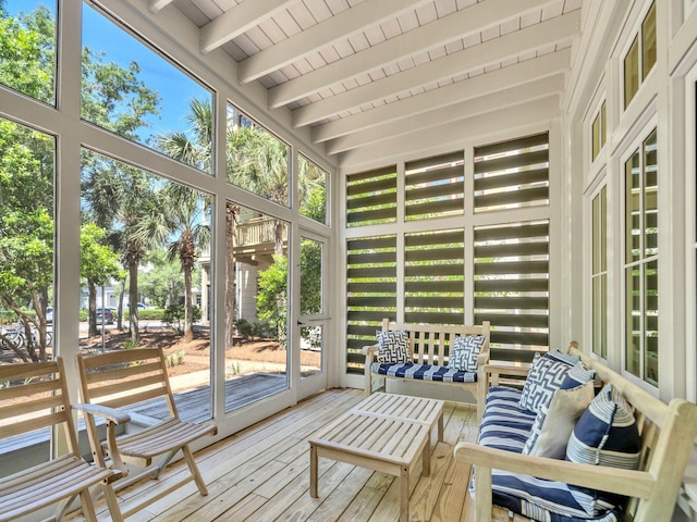 sunroom with beam ceiling, wood-type flooring, plenty of natural light, and a deck