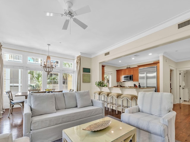 living area with ornamental molding, a chandelier, wood finished floors, ceiling fan, and recessed lighting