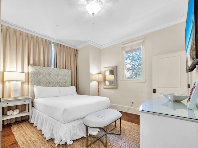 bedroom with crown molding, wood finished floors, and baseboards
