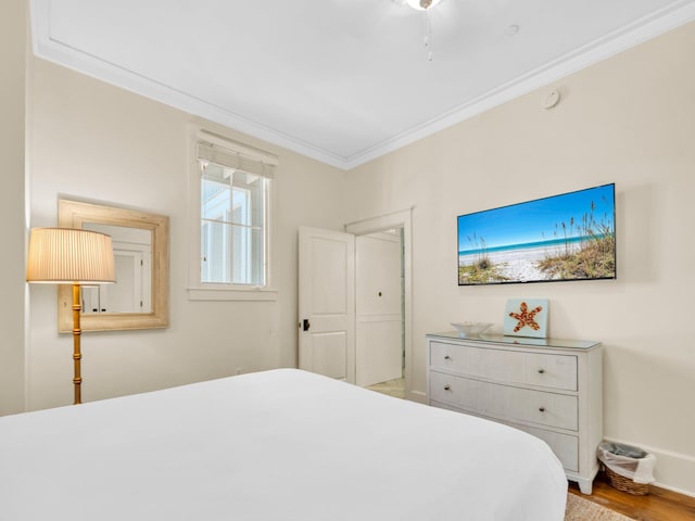 bedroom featuring crown molding, wood finished floors, and baseboards