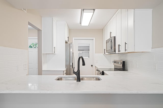 48 4th Ave, Shalimar, FL 32579 - kitchen featuring appliances with stainless steel finishes, a sink, tasteful backsplash, light stone counters, and a peninsula