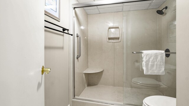 full bath featuring toilet, a shower stall, and a drop ceiling