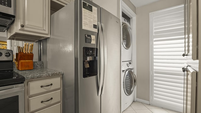 laundry room with stacked washer / drying machine and light tile patterned floors