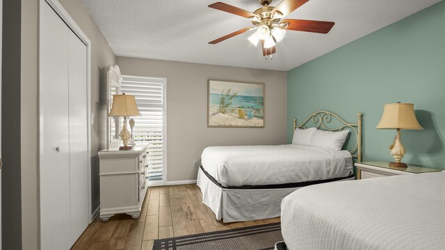 bedroom with wood finished floors, a closet, baseboards, and a ceiling fan