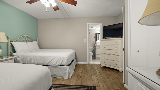 bedroom with wood finished floors, ensuite bath, a ceiling fan, and baseboards