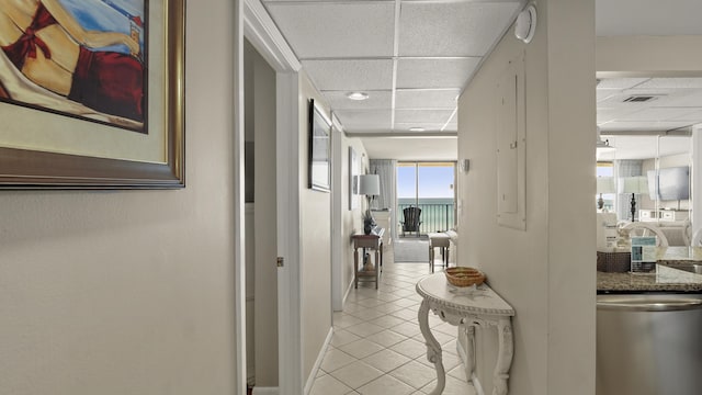 corridor featuring a drop ceiling and light tile patterned floors