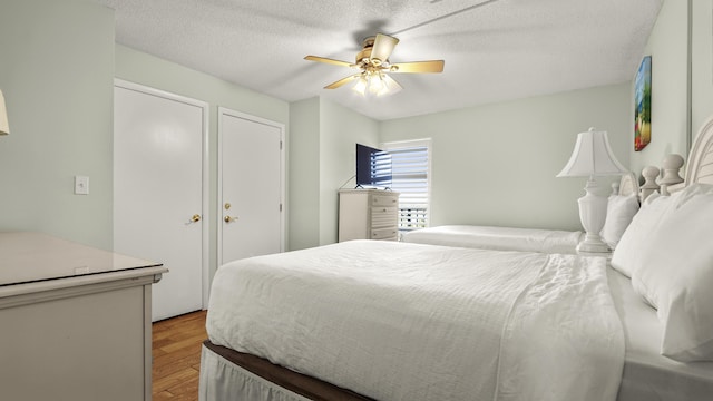 bedroom featuring light wood finished floors, a ceiling fan, and a textured ceiling