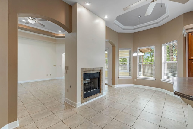 1049 Napa Way, Niceville, FL 32578 - unfurnished living room featuring a raised ceiling, a ceiling fan, light tile patterned floors, arched walkways, and a tiled fireplace