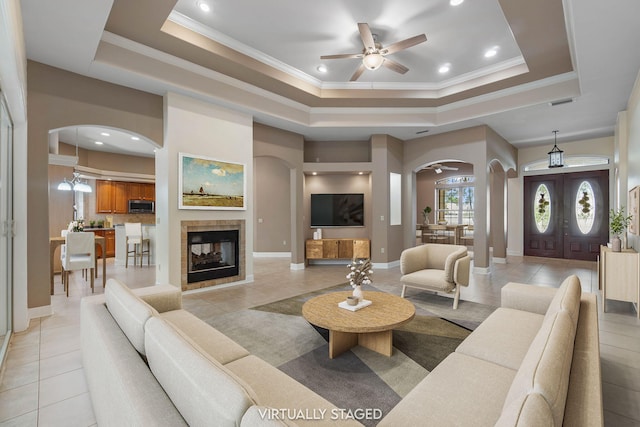 1049 Napa Way, Niceville, FL 32578 - living room featuring arched walkways, a tray ceiling, a ceiling fan, light tile patterned floors, and crown molding