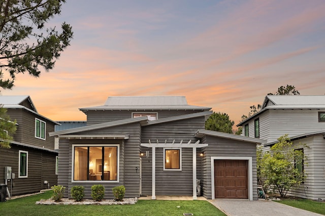 view of front of house featuring an attached garage, gravel driveway, and a lawn