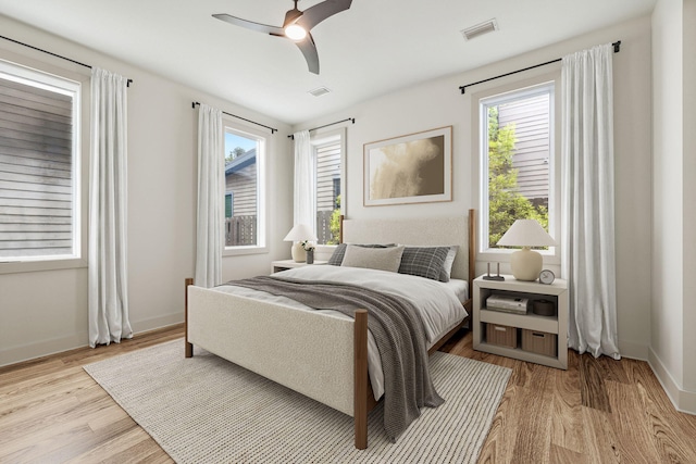 bedroom featuring wood finished floors, multiple windows, and baseboards