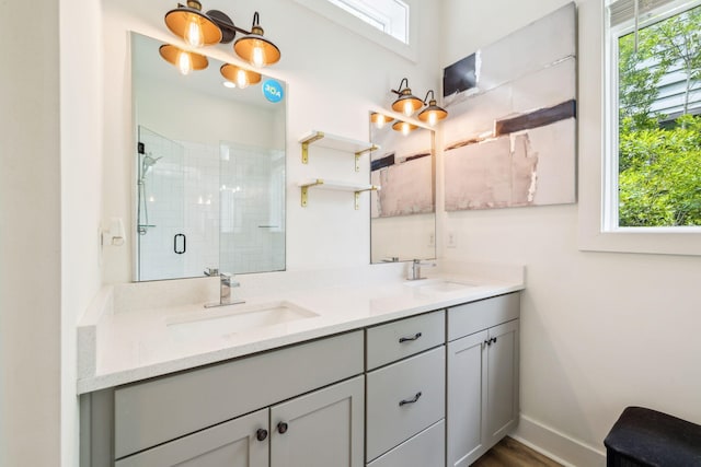 bathroom featuring a shower stall, double vanity, baseboards, and wood finished floors