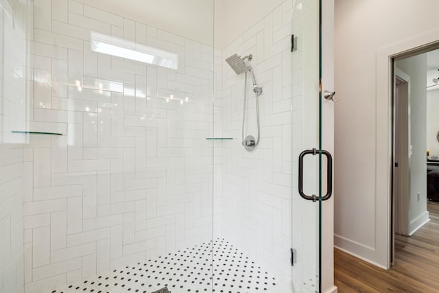 bathroom with a stall shower, baseboards, and wood finished floors