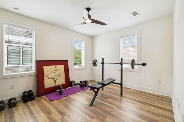 exercise room featuring healthy amount of natural light, ceiling fan, wood finished floors, and baseboards