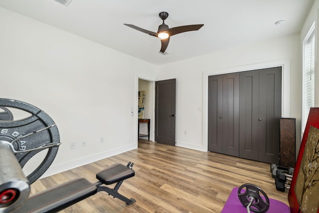 workout room with a ceiling fan, wood finished floors, and baseboards