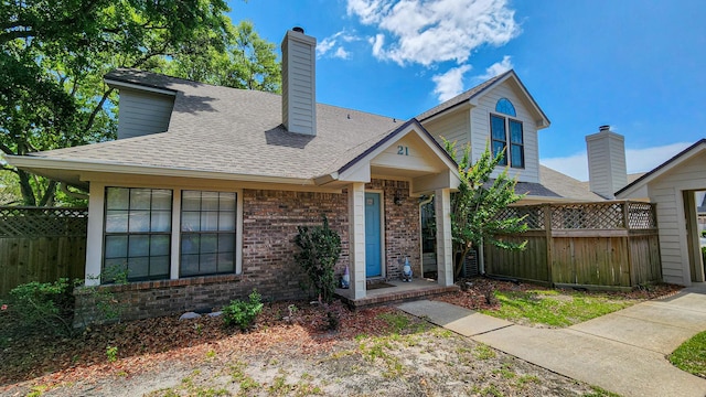 1100 Crosswinds Lndg Unit 21, Fort Walton Beach, FL 32547 - view of front of home featuring fence, a chimney, brick siding, and roof with shingles
