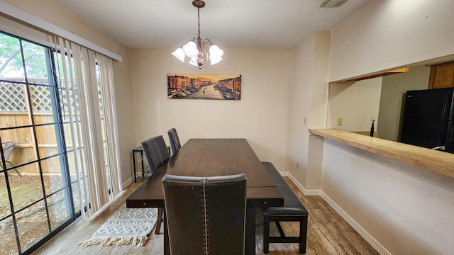 1100 Crosswinds Lndg Unit 21, Fort Walton Beach, FL 32547 - dining space with a chandelier, wood finished floors, baseboards, and a textured ceiling