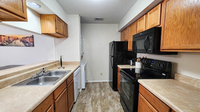 1100 Crosswinds Lndg Unit 21, Fort Walton Beach, FL 32547 - kitchen with black appliances, light wood-style floors, light countertops, a textured ceiling, and a sink