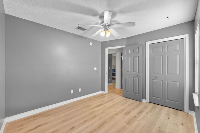 9 5th Ave, Shalimar, FL 32579 - unfurnished bedroom featuring light wood-type flooring, baseboards, a textured ceiling, a closet, and a ceiling fan