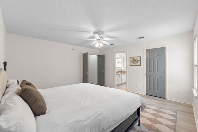 9 5th Ave, Shalimar, FL 32579 - bedroom featuring light wood finished floors, baseboards, ensuite bathroom, a ceiling fan, and a textured ceiling