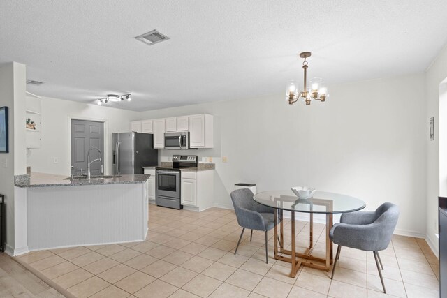 9 5th Ave, Shalimar, FL 32579 - kitchen with appliances with stainless steel finishes, a sink, white cabinets, a chandelier, and a peninsula