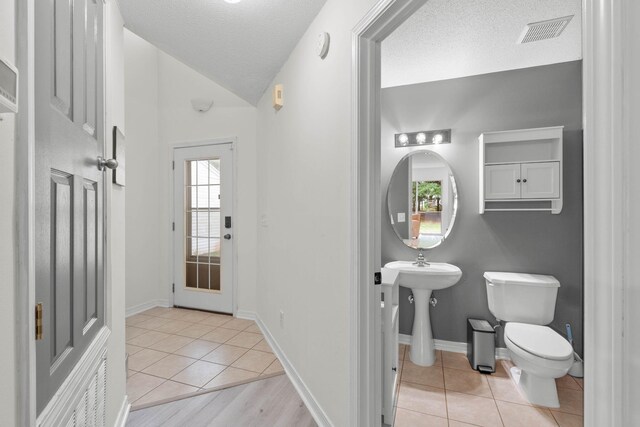 9 5th Ave, Shalimar, FL 32579 - half bath with toilet, tile patterned flooring, a textured ceiling, vaulted ceiling, and baseboards