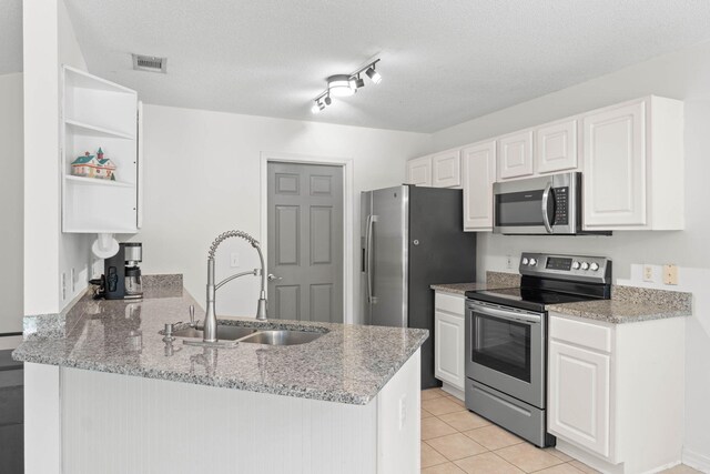 9 5th Ave, Shalimar, FL 32579 - kitchen featuring appliances with stainless steel finishes, a sink, open shelves, a peninsula, and white cabinets