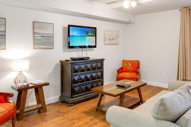 living room with a ceiling fan, light wood-style flooring, and baseboards