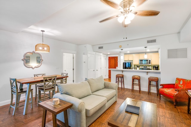 living room featuring ceiling fan, hardwood / wood-style floors, and baseboards