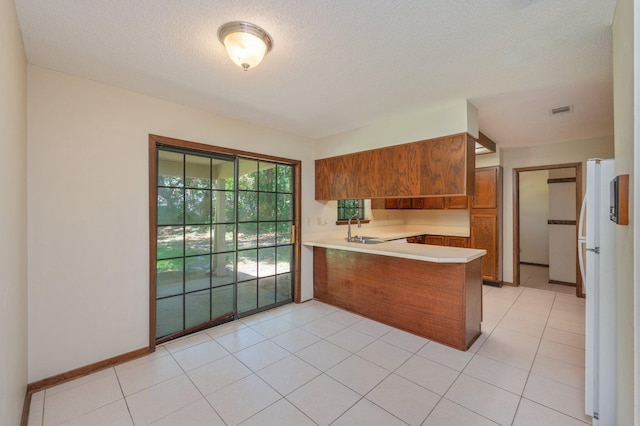 829 S Turnberry Cv, Niceville, FL 32578 - kitchen with a peninsula, brown cabinetry, light countertops, a sink, and freestanding refrigerator