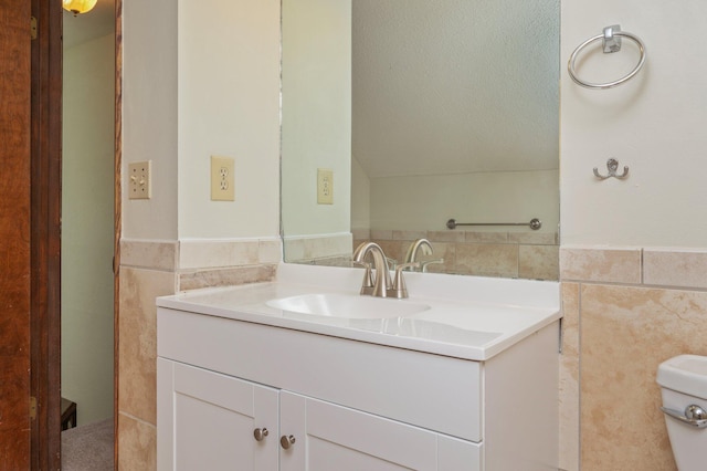 829 S Turnberry Cv, Niceville, FL 32578 - bathroom with tile walls, vanity, wainscoting, vaulted ceiling, and toilet