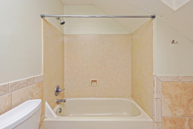 829 S Turnberry Cv, Niceville, FL 32578 - bathroom featuring tile walls, toilet,  shower combination, lofted ceiling, and a wainscoted wall