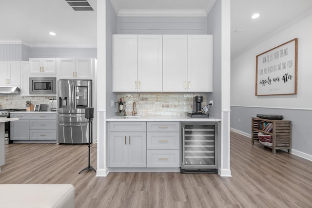 1233 Elderflower Dr, Niceville, FL 32578 - indoor wet bar with appliances with stainless steel finishes, beverage cooler, under cabinet range hood, light wood-type flooring, and recessed lighting